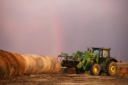 tractor storing round hay bales